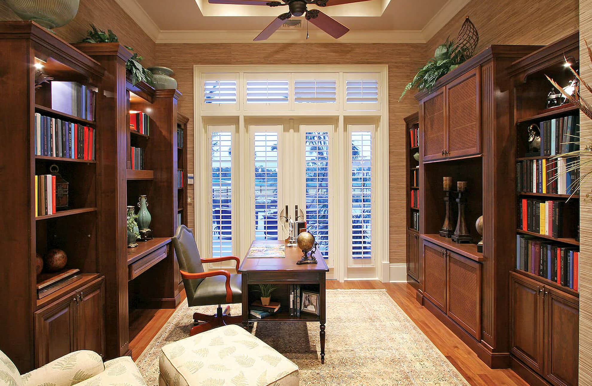 A classic home office with wood built-in bookcases with cabinets from Bertch.