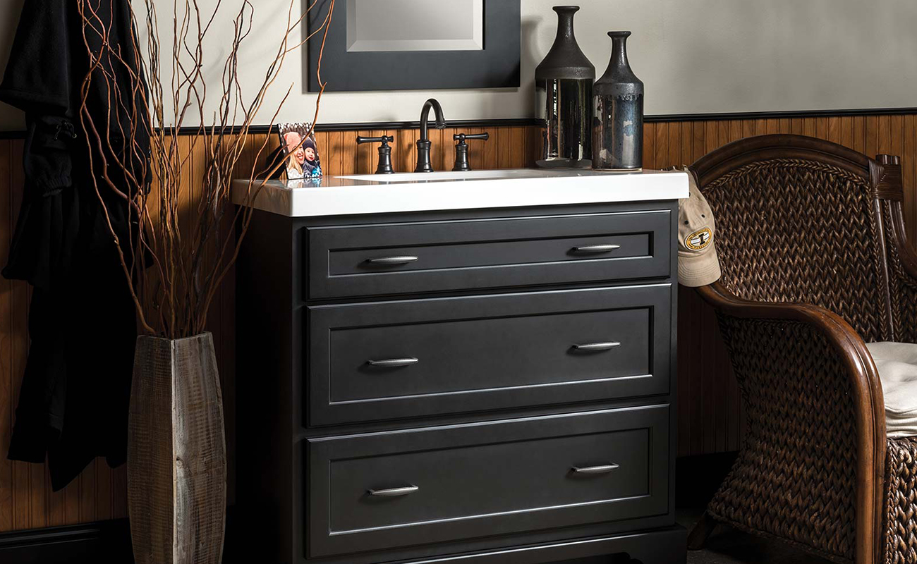 A dresser styled bathroom vanity with a black painted finish and furniture style details.