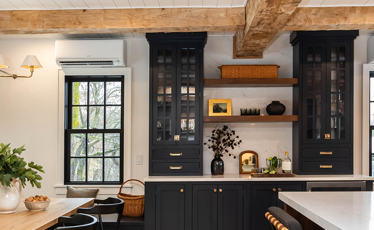 A traditional styled beverage station and storage space near the dining room with black painted cabinets.