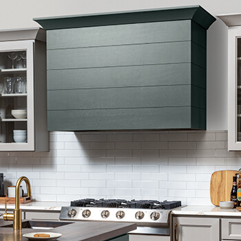 A close up of a modern wood hood with shiplap details and a hunter green painted finish.