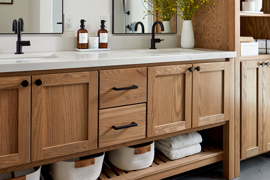 A honey oak vanity with dual sinks and a furniture style look with an open floor shelf.