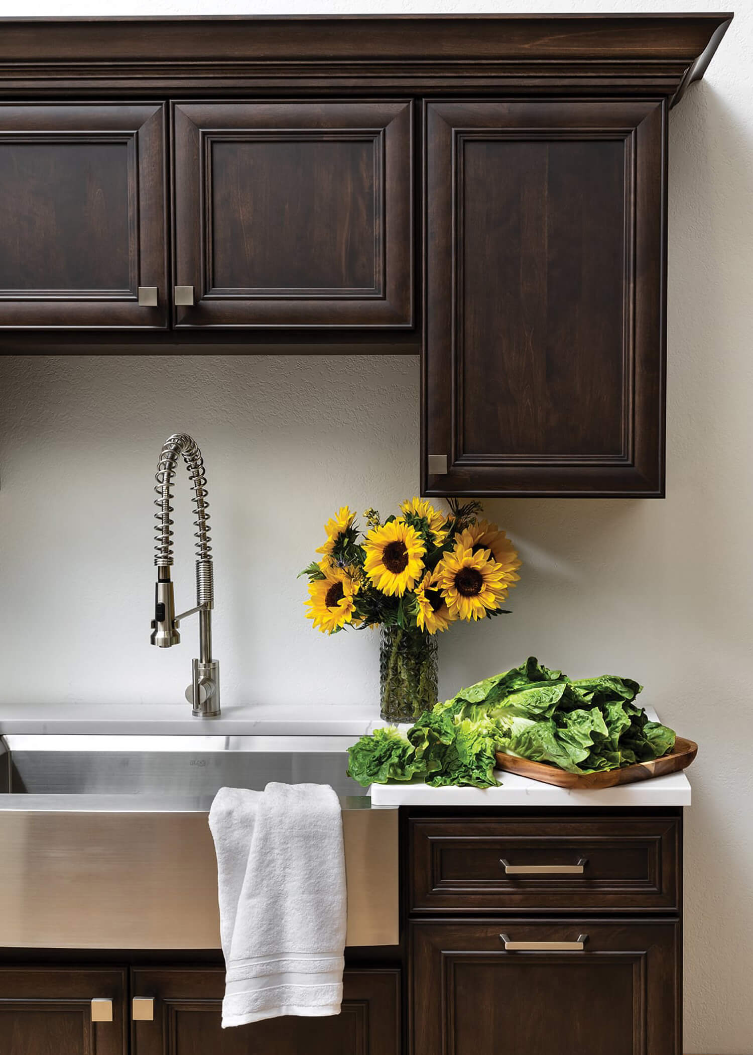 Dark stained kitchenette with a stainles steel drop in sink and sunflowers on the counter.