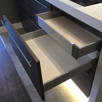 A cabinet with stainless steel drawers and a hidden drawer within a drawer.