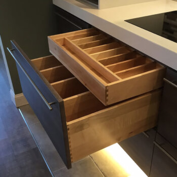 This hidden kitchen drawer with added dividers offers a discreet but highly organized storage solution for utensils and misc. items.