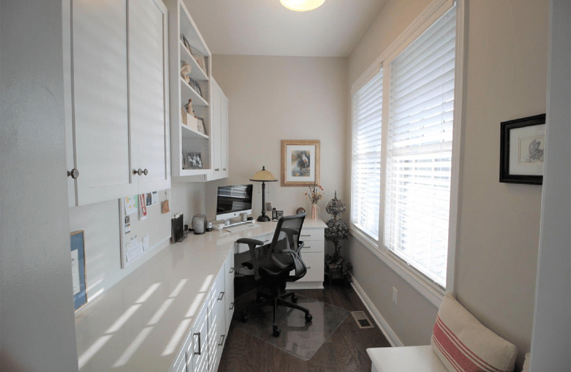 A one wall, all-white home office in a narrow space featuring white painted shaker style cabinets.