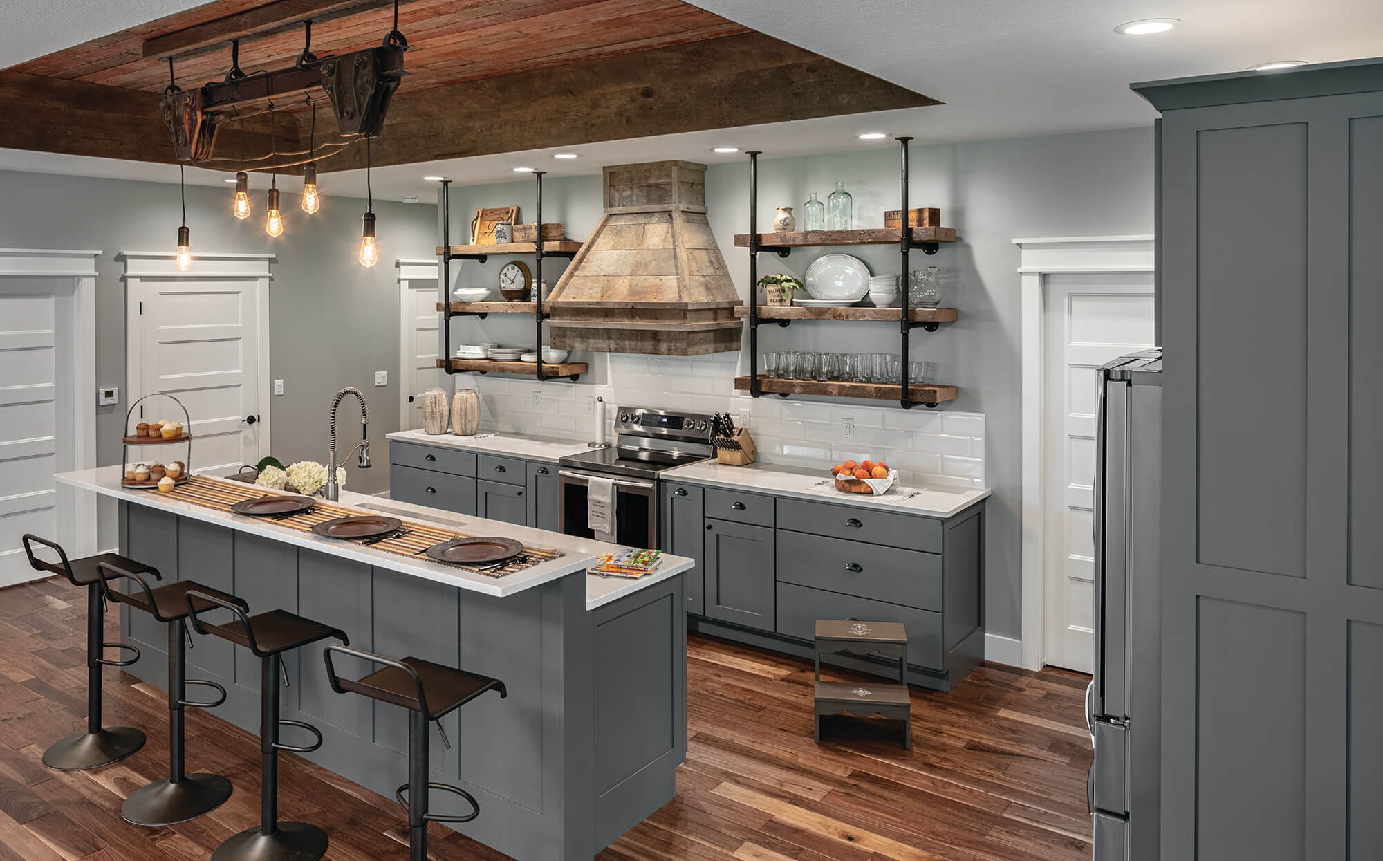 An industrial styled kitchen remodel with barn wood accents, grey painted shaker cabinets, and open shelving.