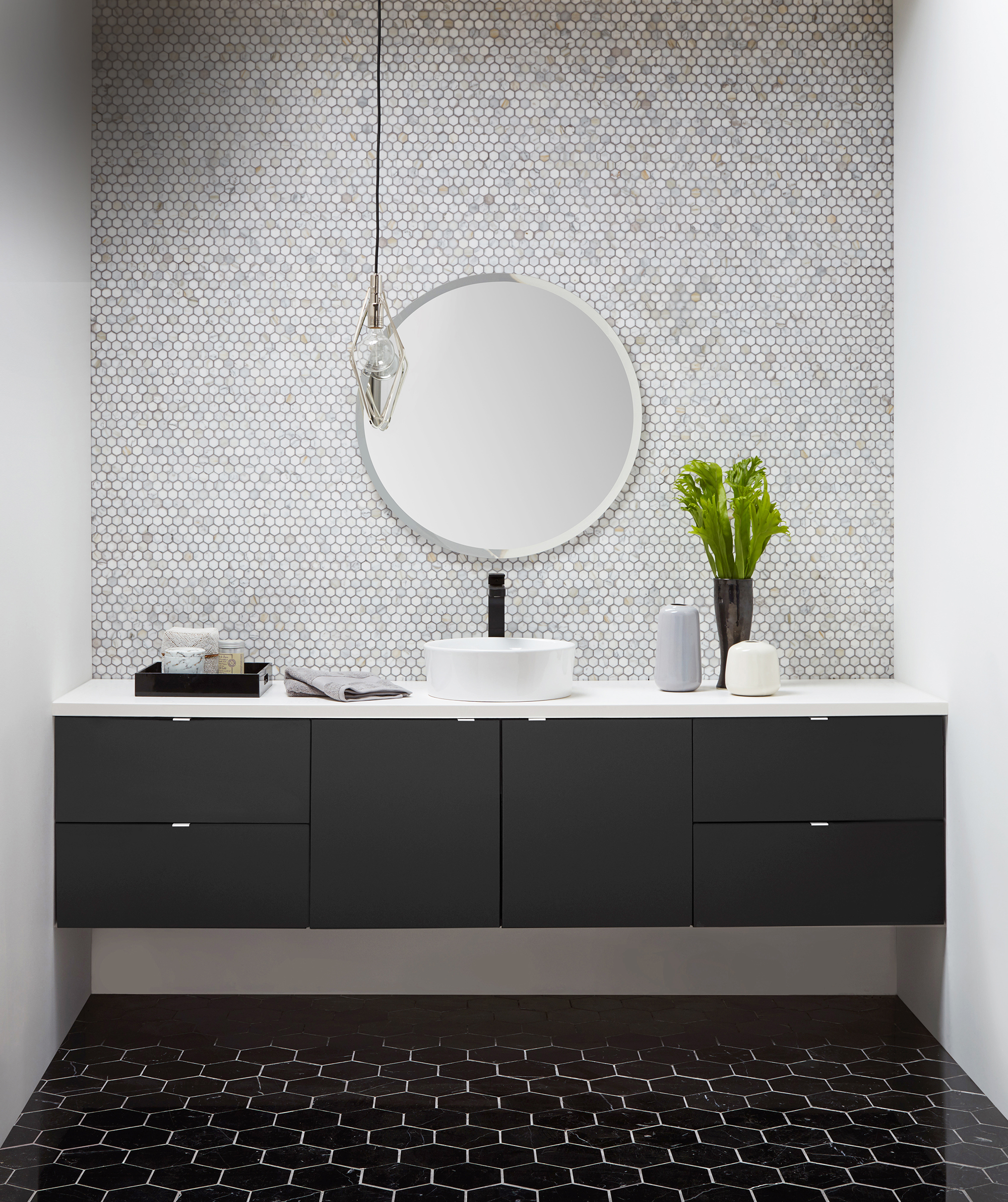 A wall-hung floating vanity with black painted cabinets shown in a modern styled bathroom design.