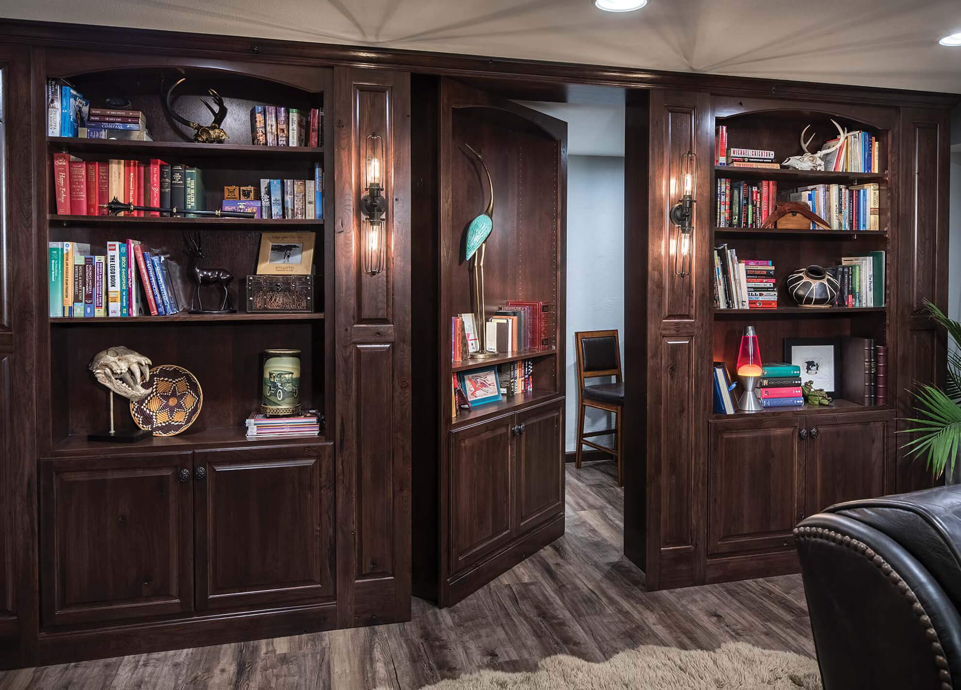 Dark brown stained built-in book shelves with secret home office door.